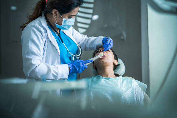 Dentist using the latest dental technology as she treats a young woman during appointment at dentist's office in India.